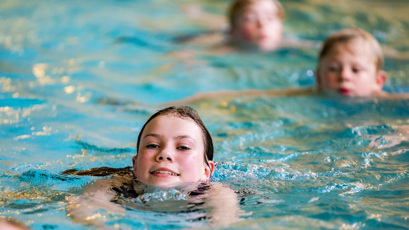 Barn simtränar i bassängen på Kristianstads badrike