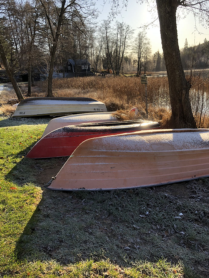Mindre båtar ligger i gräset med kölen uppåt.