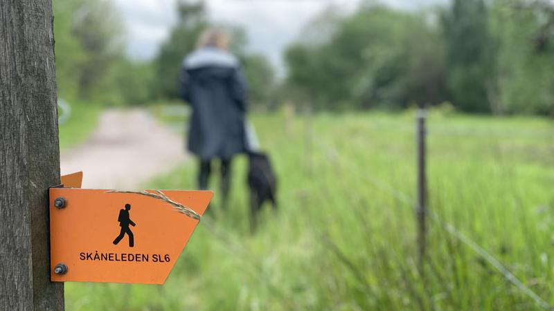 Kvinna med svart hund vandrar på Skåneleden 