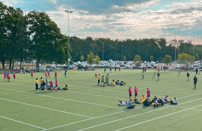 Samling av barn och ungdomar på idrottsplatsen inför dagens aktiviteter på C4-lägret 2023