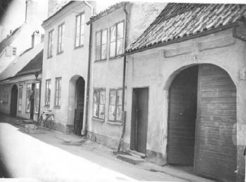 Allön 16 (tid. 5 o. 6). Tvåvåningshuset t.v. nr 5 samt två- och envåningshusen t.h. nr 6, Västra Vallgatan 9 och 11, senast 1939. (RM)