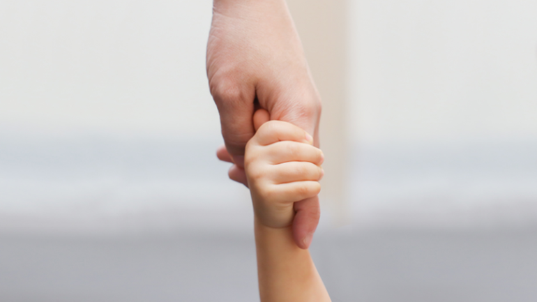 En vuxen hand som håller i en barnhand