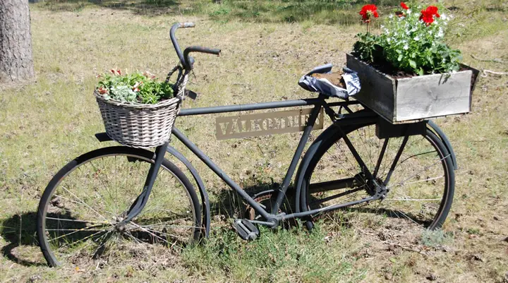 Bild på en cykel smyckad med blommor och texten Välkommen på.